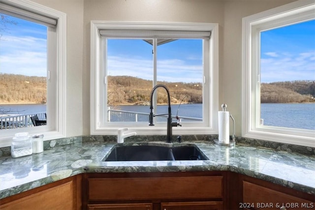 interior details featuring sink, stone counters, and a water view