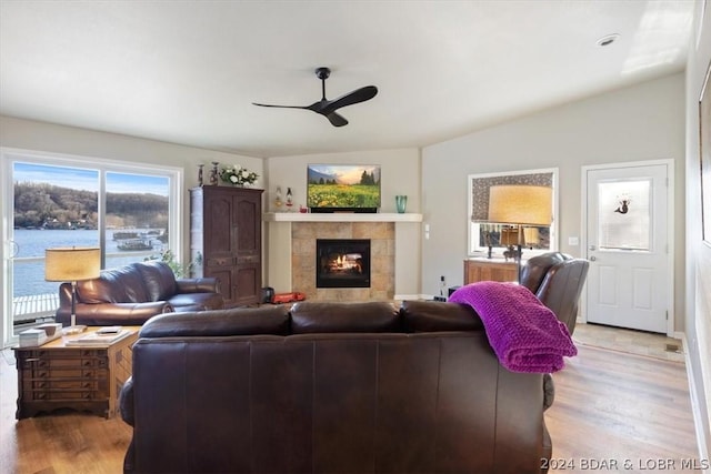 living room with ceiling fan, light hardwood / wood-style flooring, a water view, and a fireplace