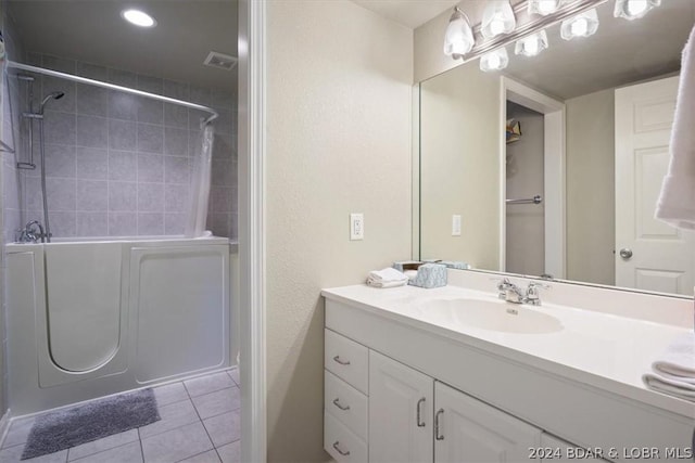 bathroom featuring tile patterned flooring, tiled shower, and vanity