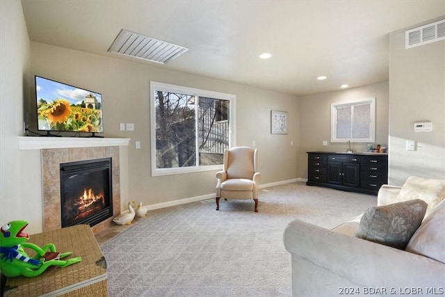 living room featuring a tiled fireplace, light carpet, and sink