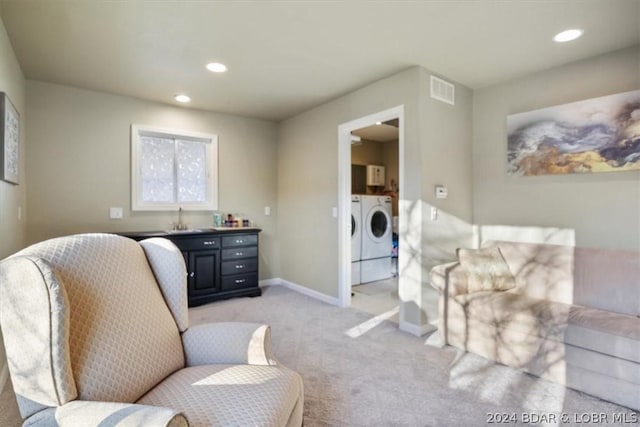 living area featuring washer and dryer, light carpet, and sink