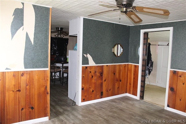 interior space with wood-type flooring, ceiling fan, and wood walls