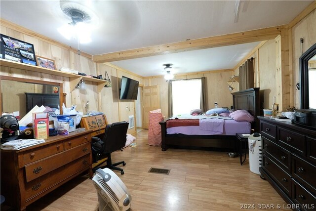 bedroom with beam ceiling, wooden walls, and light wood-type flooring