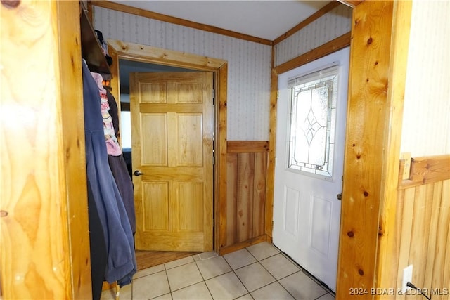 entryway with crown molding and light tile patterned floors