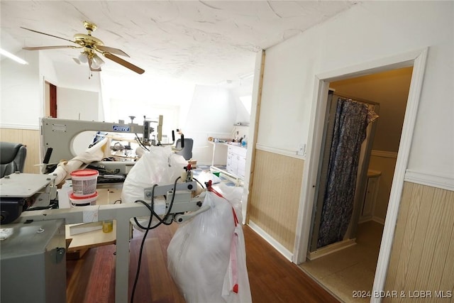 misc room featuring wood-type flooring, ceiling fan, and wood walls