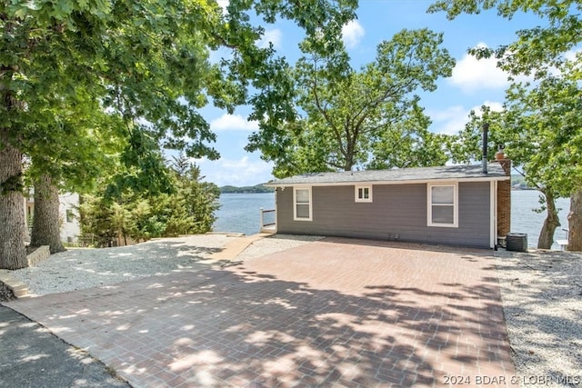 rear view of house with central air condition unit and a water view