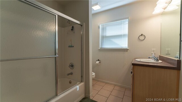 full bathroom with enclosed tub / shower combo, vanity, tile patterned floors, and toilet