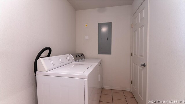 washroom featuring electric panel, washer and clothes dryer, and light tile patterned floors