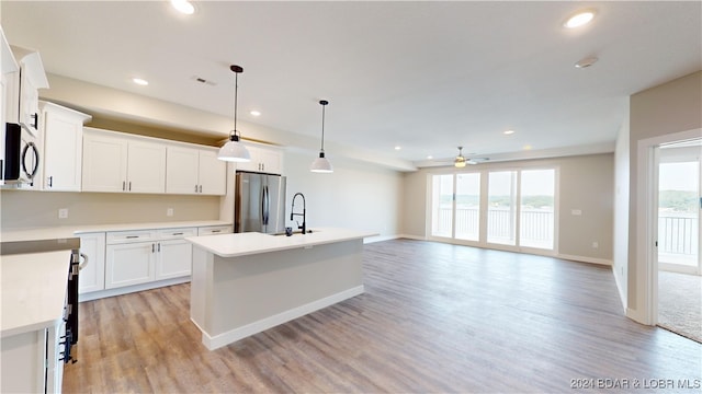 kitchen featuring appliances with stainless steel finishes, white cabinetry, pendant lighting, ceiling fan, and a kitchen island with sink