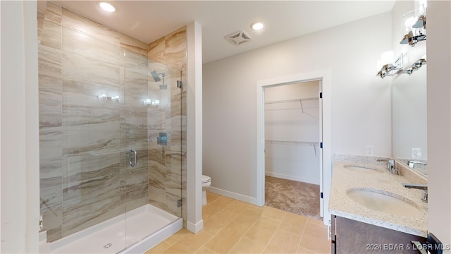 bathroom with a shower with door, toilet, vanity, and tile patterned floors