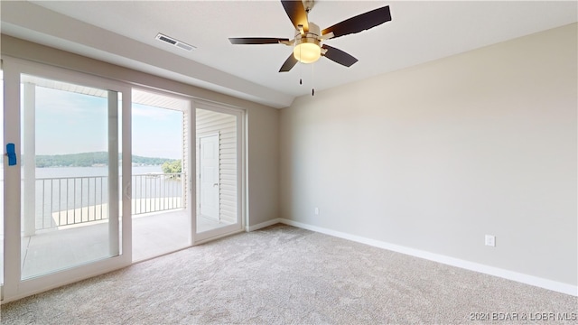 carpeted spare room with a water view and ceiling fan