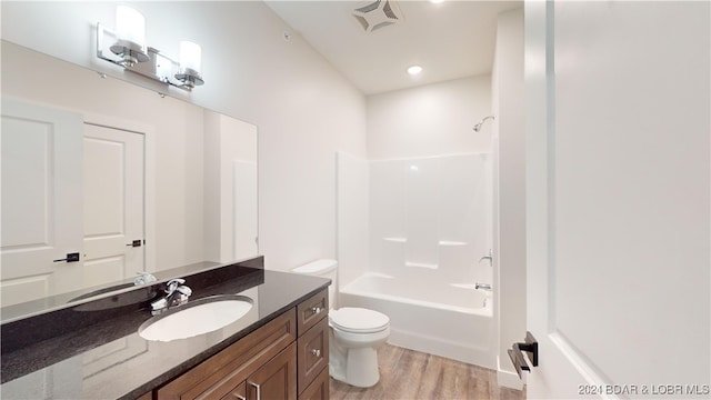 full bathroom with shower / tub combination, vanity, toilet, and hardwood / wood-style flooring