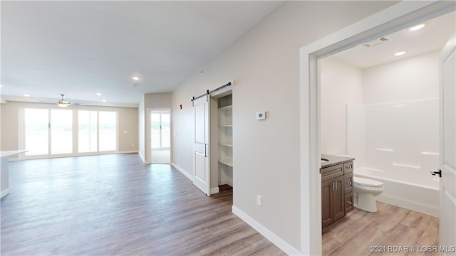 hallway featuring a barn door and light hardwood / wood-style flooring