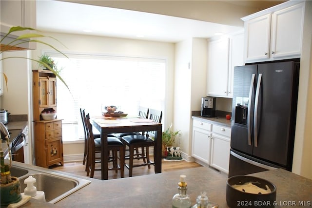 kitchen featuring plenty of natural light, stainless steel fridge, and white cabinets