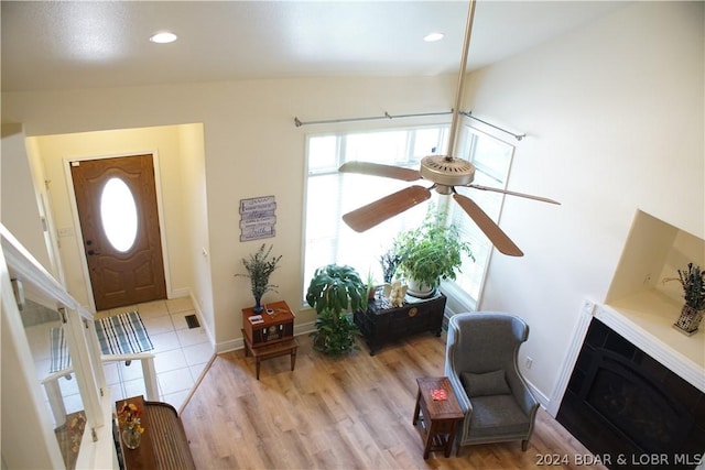 foyer entrance featuring recessed lighting, a fireplace, a ceiling fan, baseboards, and light wood finished floors