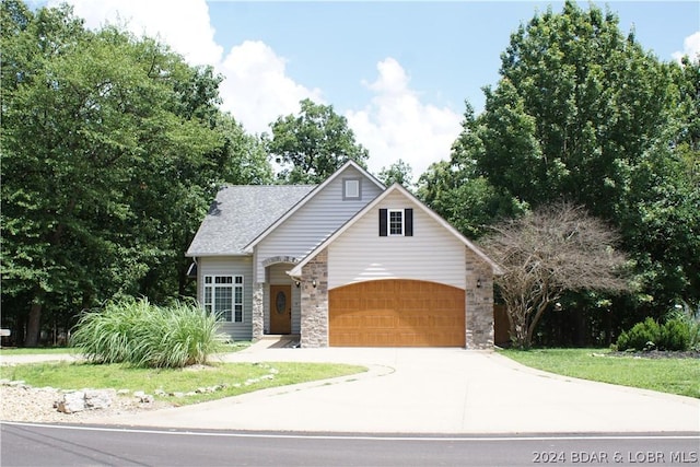 view of front of property featuring stone siding, concrete driveway, and a front lawn