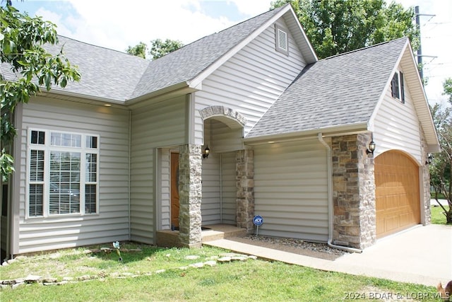 view of front of home featuring a shingled roof, stone siding, and an attached garage