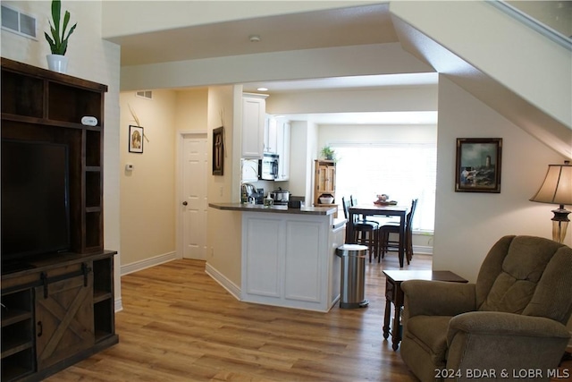 kitchen featuring visible vents, light wood-style flooring, stainless steel microwave, and white cabinetry