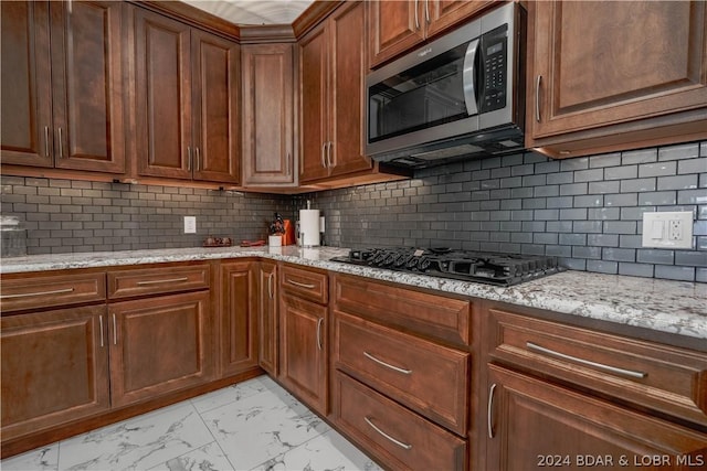 kitchen with black gas cooktop, decorative backsplash, and light stone countertops