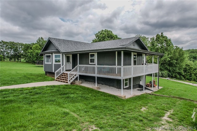 view of front of house with a patio, a shingled roof, and a front yard