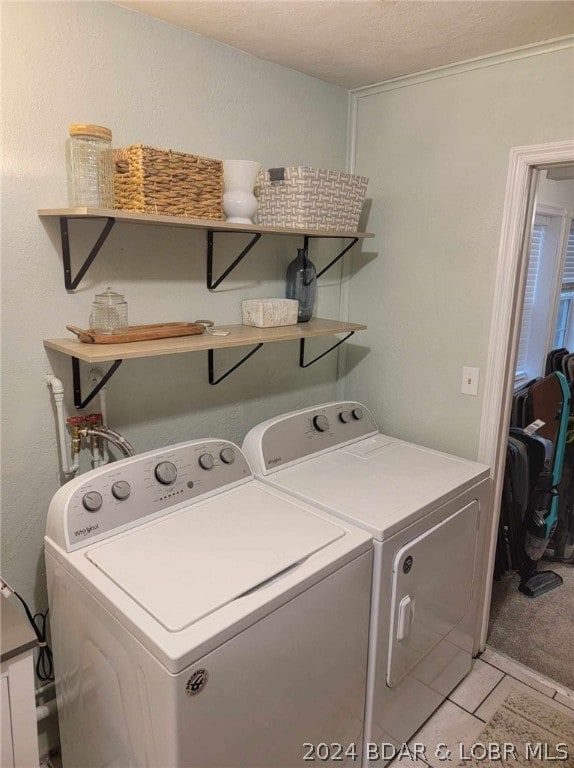 clothes washing area featuring light tile patterned flooring and washer and clothes dryer