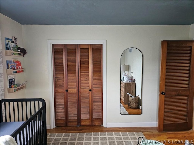 bedroom featuring a closet, a crib, and hardwood / wood-style floors