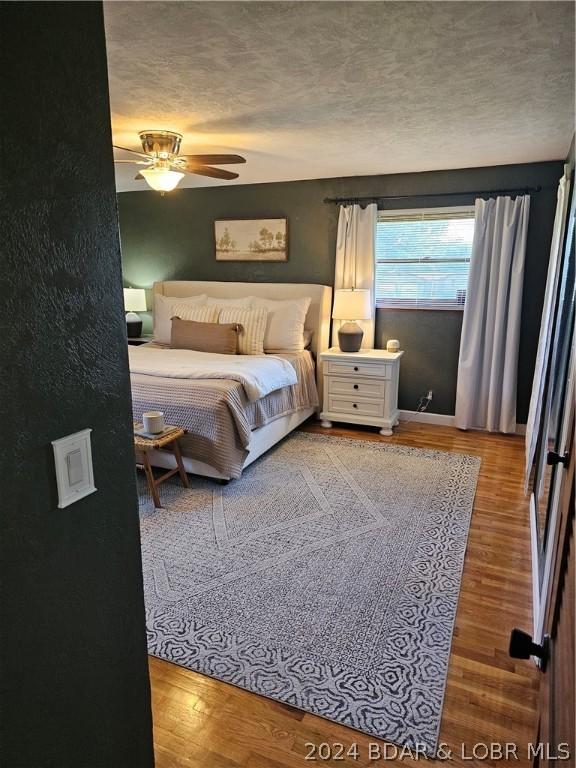 bedroom featuring light wood-type flooring, ceiling fan, and a textured ceiling