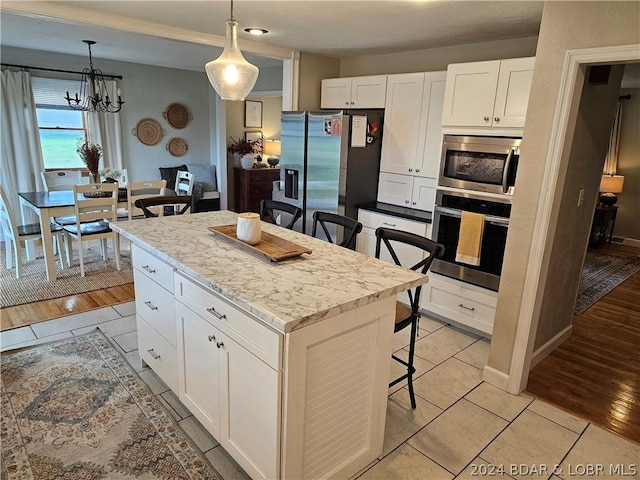 kitchen featuring stainless steel appliances, white cabinets, a kitchen breakfast bar, and a center island