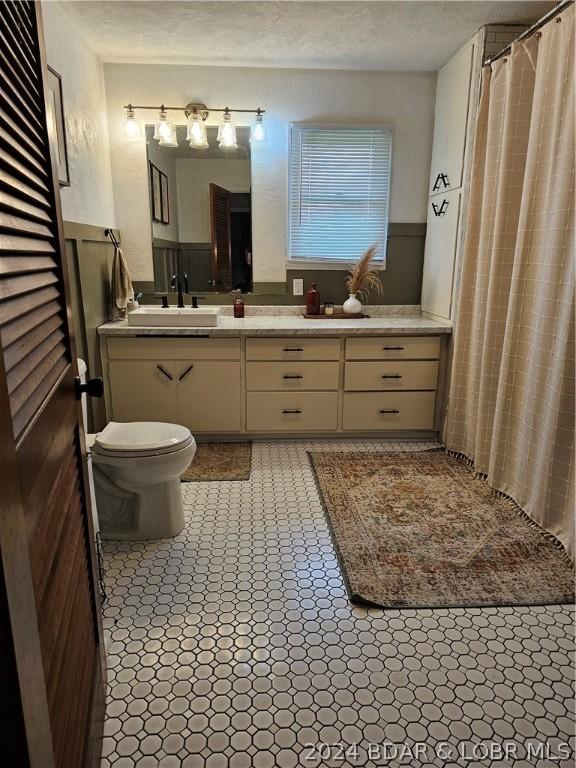 bathroom with toilet, a textured ceiling, wooden walls, and vanity