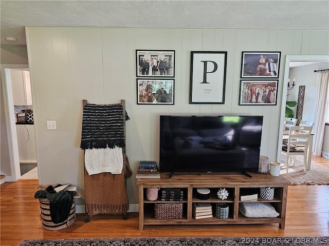 living room with a textured ceiling, wood walls, and wood-type flooring