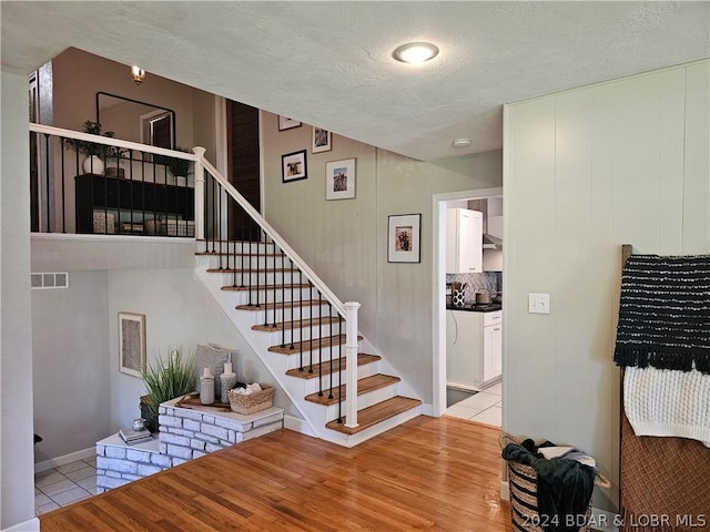 staircase featuring a textured ceiling and hardwood / wood-style floors