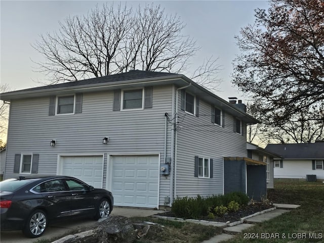 view of side of home with a garage and central AC