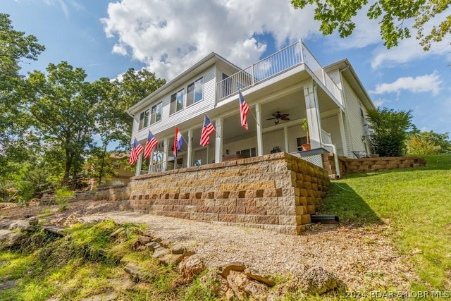 view of front facade featuring a front lawn, a balcony, and ceiling fan