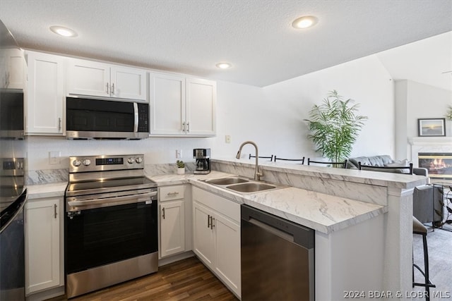 kitchen featuring stainless steel appliances, white cabinetry, sink, and kitchen peninsula