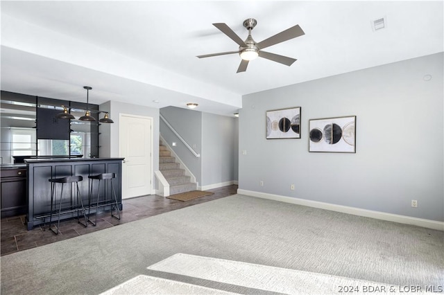 carpeted living room with bar area and ceiling fan