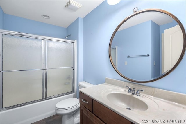 full bathroom featuring vanity, bath / shower combo with glass door, and toilet