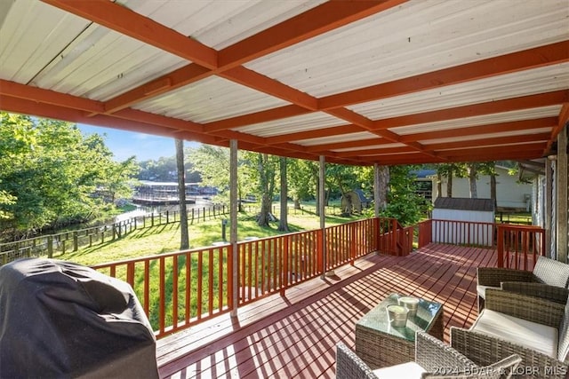 wooden deck with a lawn, an outdoor hangout area, a storage unit, and grilling area