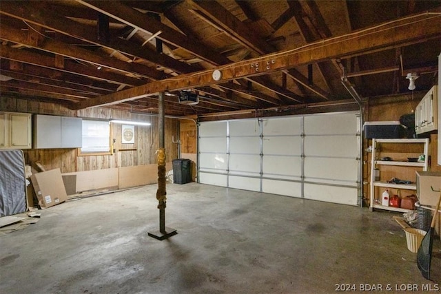 garage with a garage door opener and wooden walls