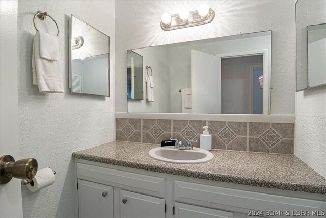 1465 Easy St, Osage Beach, MO 65065 - bathroom featuring backsplash, vanity, and a textured wall
