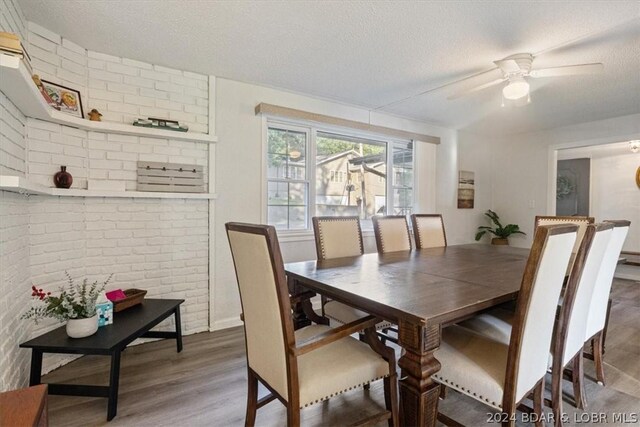 dining room featuring a textured ceiling, ceiling fan, dark hardwood / wood-style flooring, and brick wall