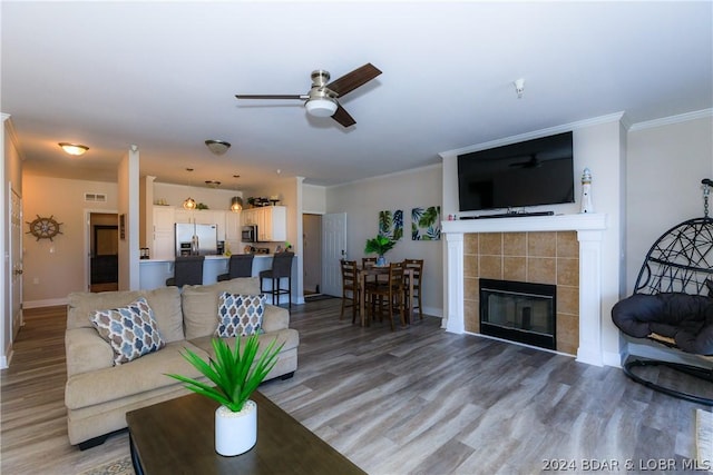 living room featuring crown molding, a fireplace, ceiling fan, and hardwood / wood-style flooring