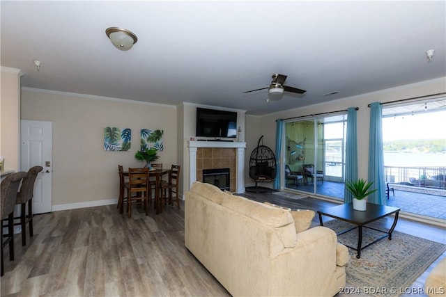 living room featuring hardwood / wood-style flooring, ceiling fan, ornamental molding, and a fireplace