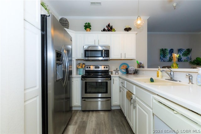 kitchen featuring white cabinetry, sink, hanging light fixtures, stainless steel appliances, and ornamental molding