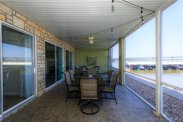 sunroom featuring a water view and ceiling fan