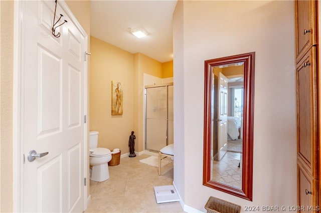 bathroom featuring toilet, a shower with door, and tile patterned flooring