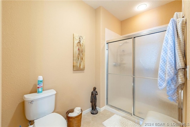 bathroom with tile patterned floors, toilet, and a shower with shower door