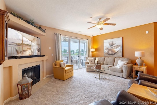 living room with a textured ceiling, ceiling fan, light colored carpet, and a fireplace