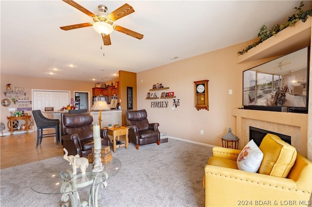 living room featuring ceiling fan, light carpet, and a tiled fireplace