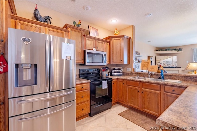 kitchen with light tile patterned flooring, appliances with stainless steel finishes, sink, and a textured ceiling