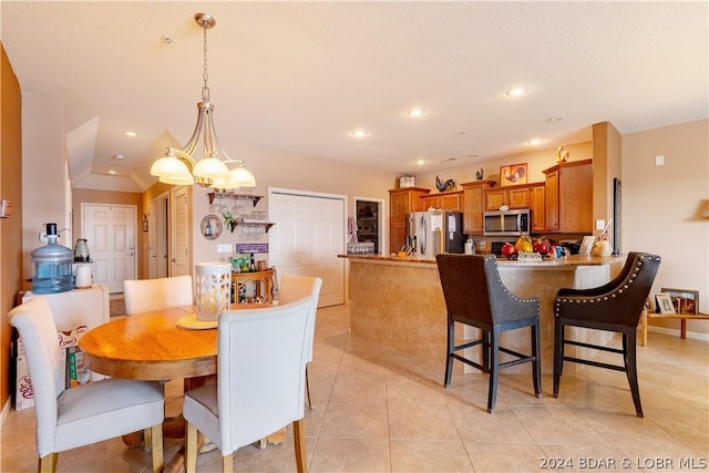 tiled dining room with vaulted ceiling and a chandelier